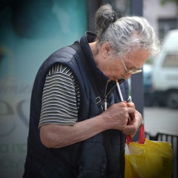 Eine ältere Dame zündet sich in einem ruhigen Moment eine Zigarette an.