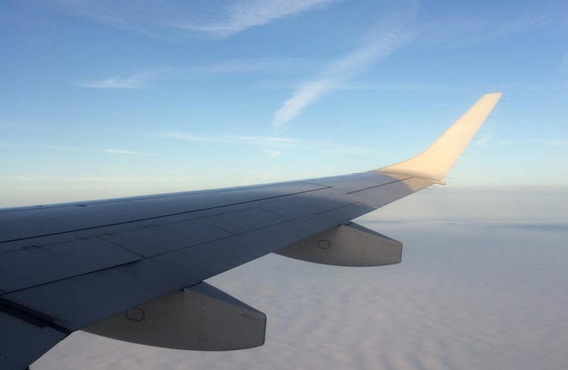 Ein Flugzeugflügel, vom Sonnenlicht angestrahlt, über den Wolken. Zu Die schlimmsten Fluggäste