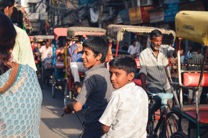 Indien in Bildern Zwei Jungen auf dem Fahrrad zwischen Fahrradrikschas in Delhi