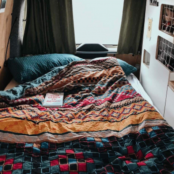 Vanlife im Camper von Vantopia Roadtrip ausgeklapptes Bett mit Bettdecke